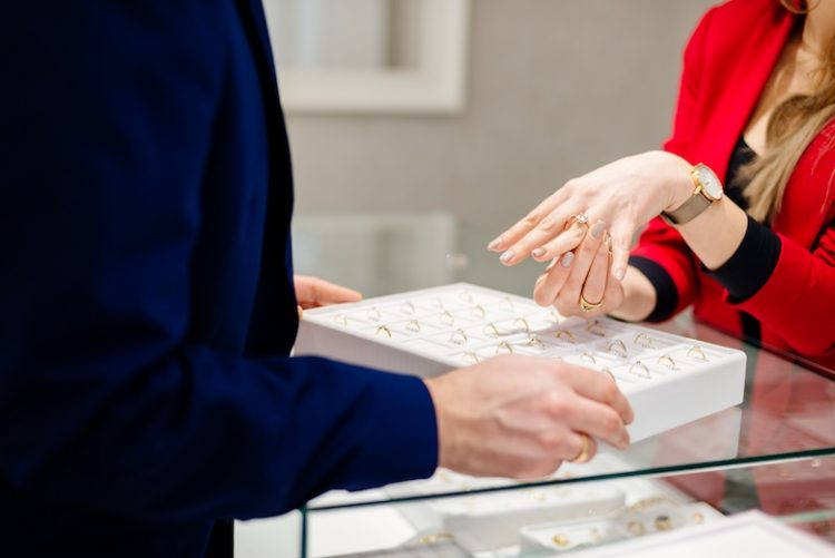 Female seller in a luxury jewelry store presents a ring.